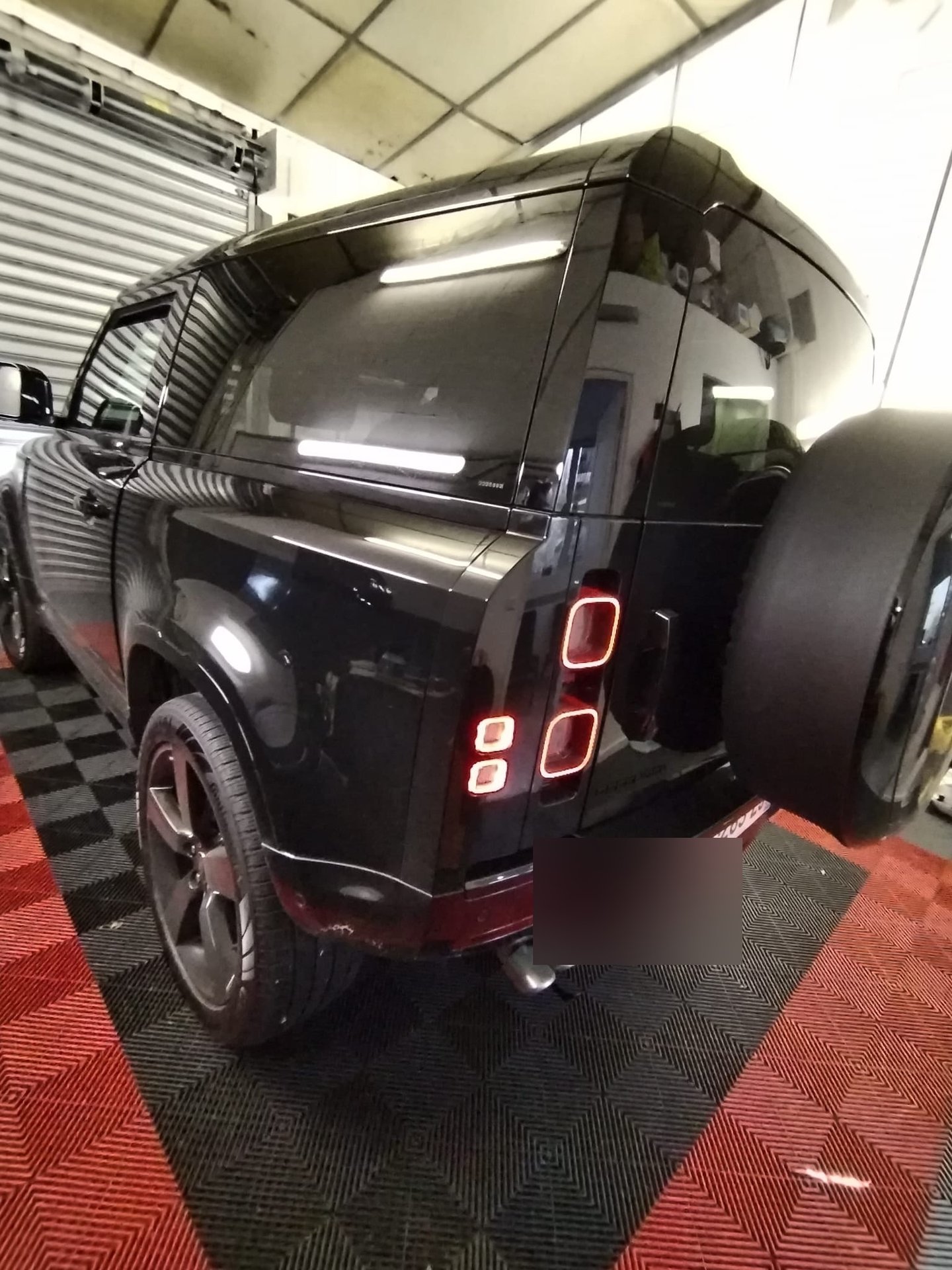 Land Rover Defender noir avec vitres teintées, roue de secours visible